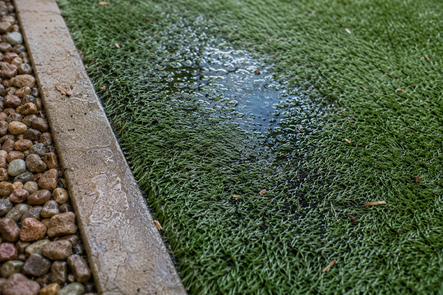 Artificial turf seam and edge area with subtle dampness after rinsing.