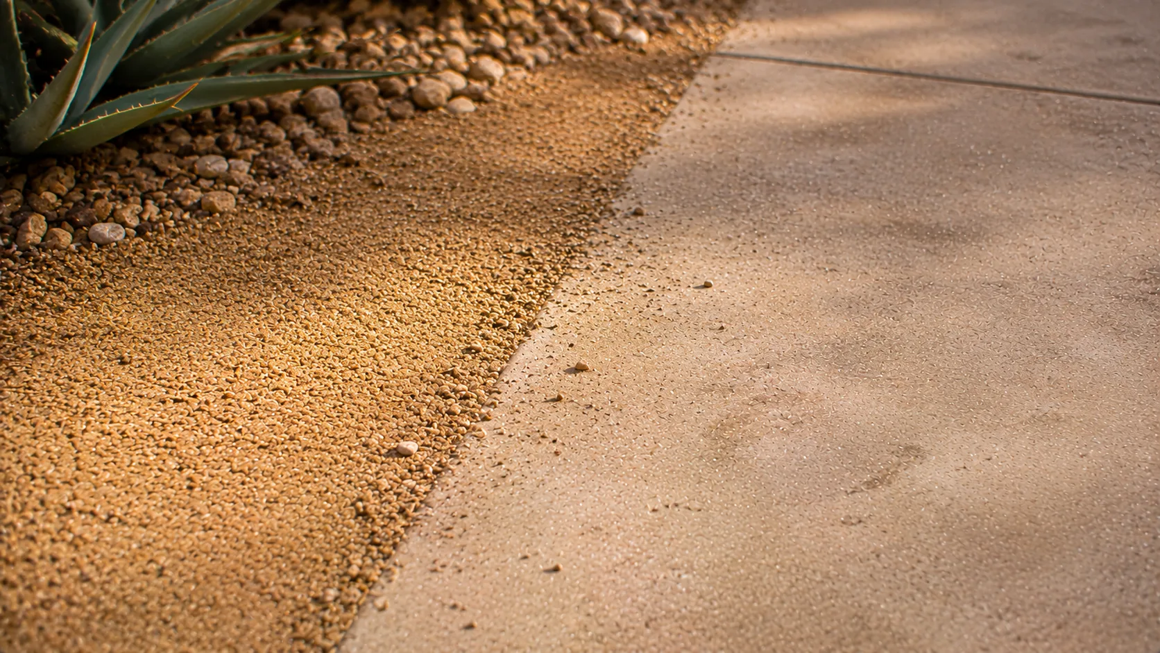 Close detail of decomposed granite meeting concrete with a clear but imperfect edge and visible surface fines.