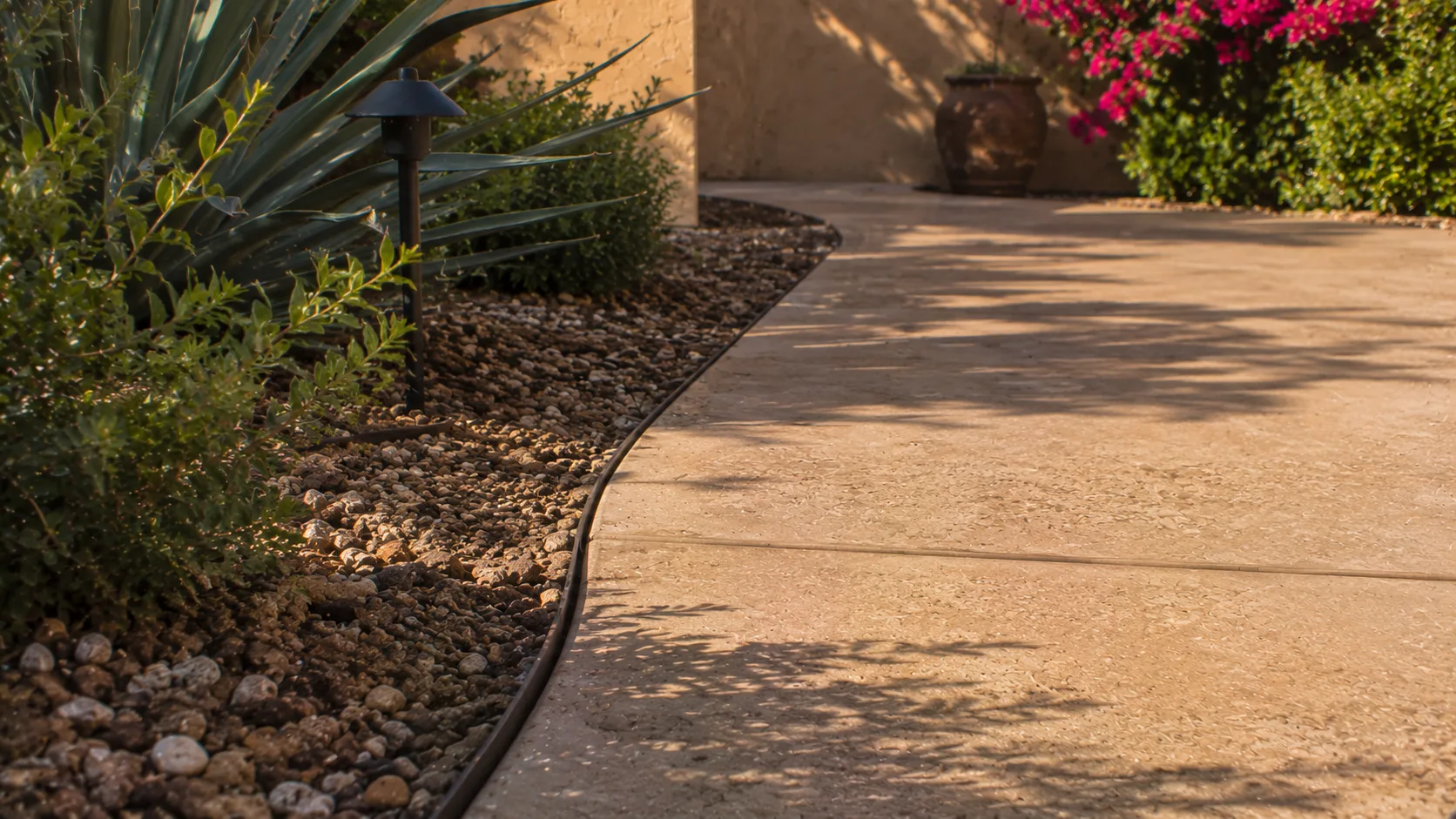 Close detail of a small backyard patio edge where hardscape meets gravel and planting.