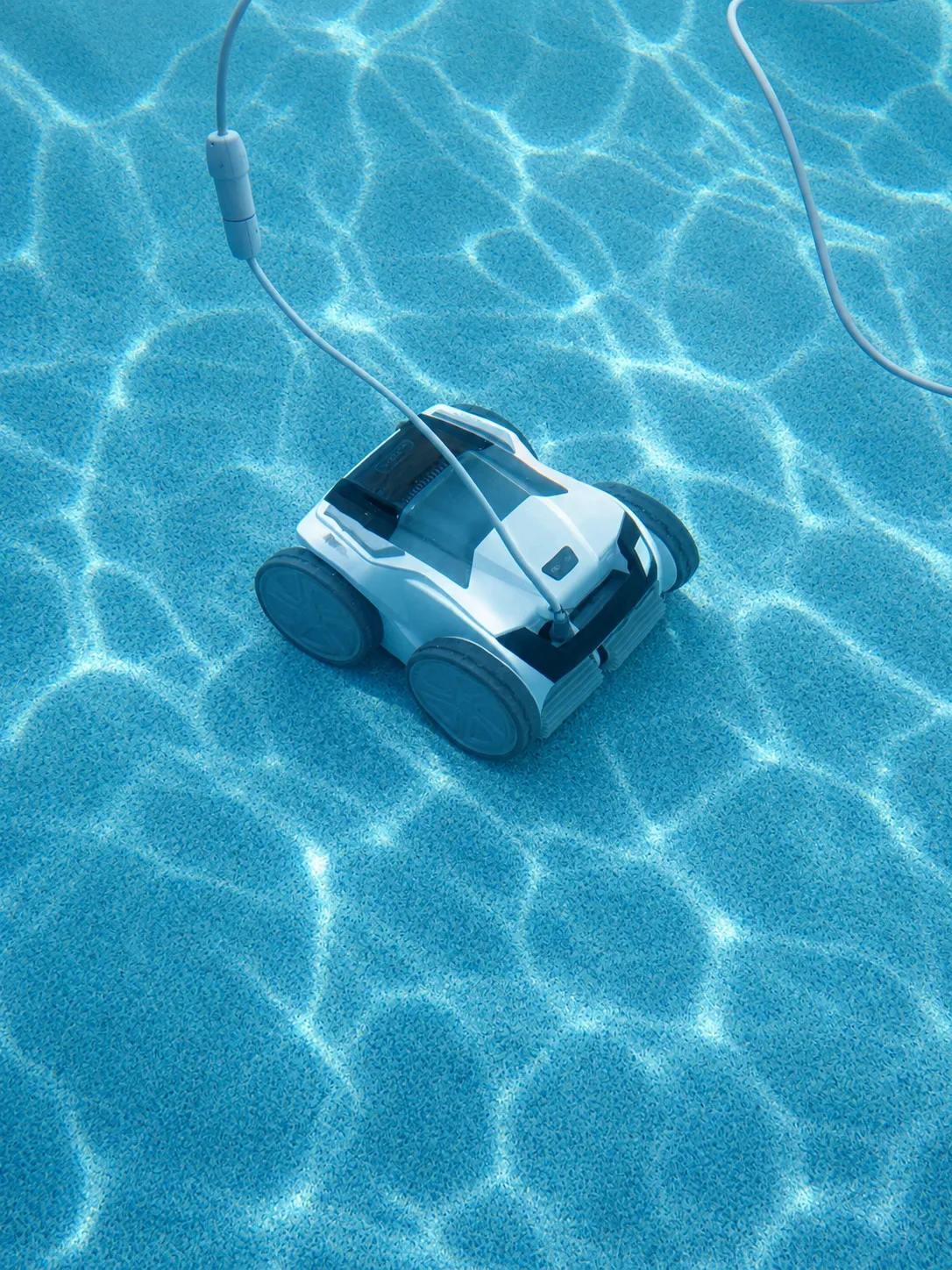 Polaris VRX iQ+ robotic pool cleaner underwater on a pebble-finish pool floor.